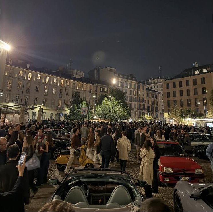 Piazza Santo Stefano piena di persone e auto storiche di sera